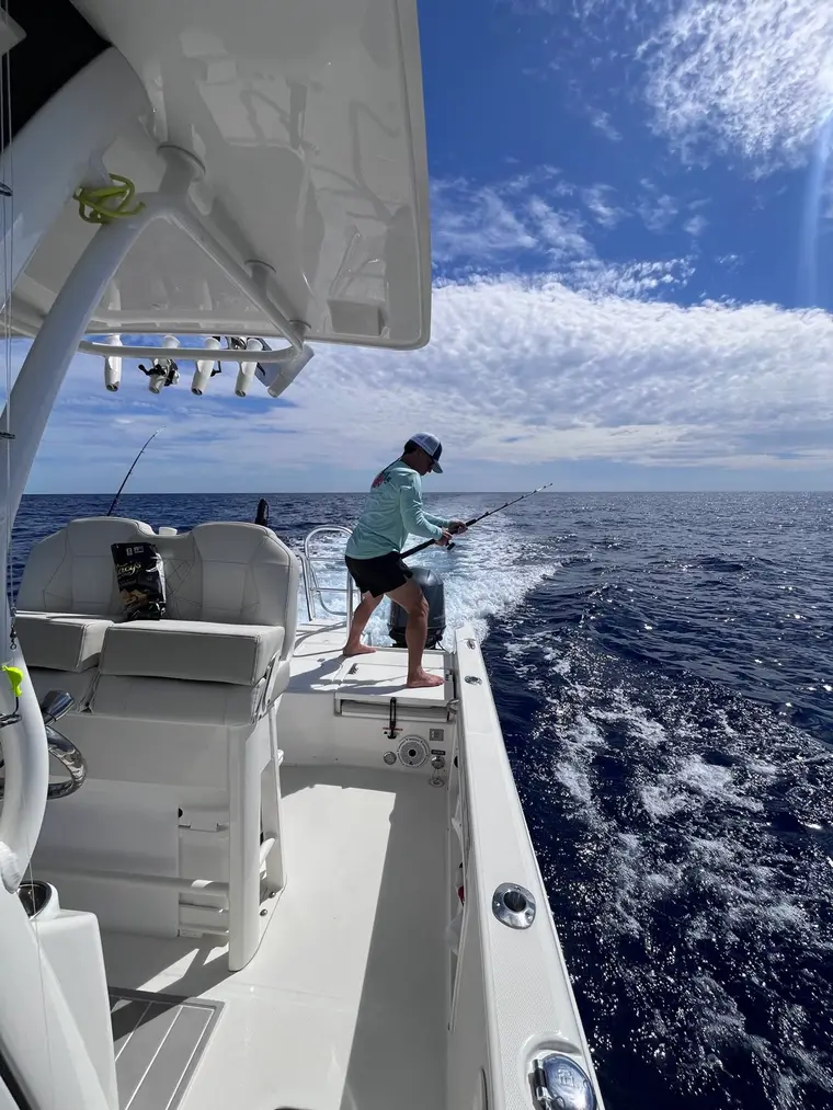 Guest fighting a fish from the gunwale on a Lulu offshore fishing trip