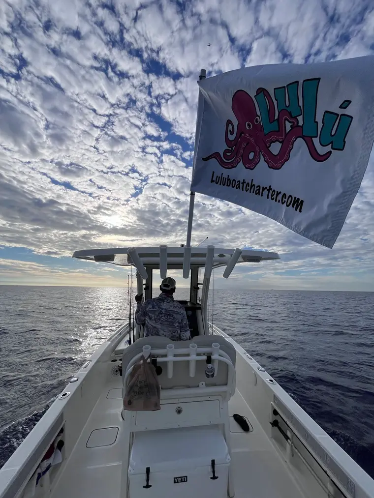 The Lulu Boat Charter flag flying offshore under a dramatic South Florida sky