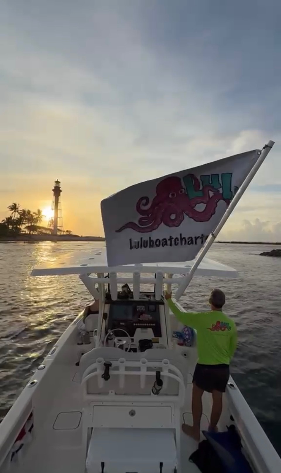 Captain waving the Lulu Boat Charter flag at Hillsboro Lighthouse at sunset
