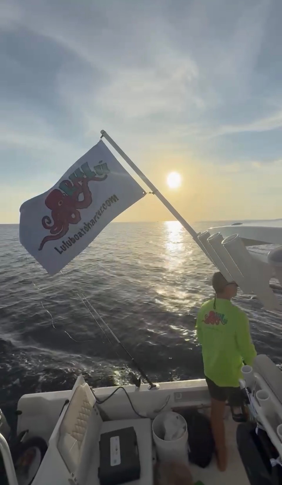 Lulu Boat Charter branded flag flying at sea during a South Florida sunset