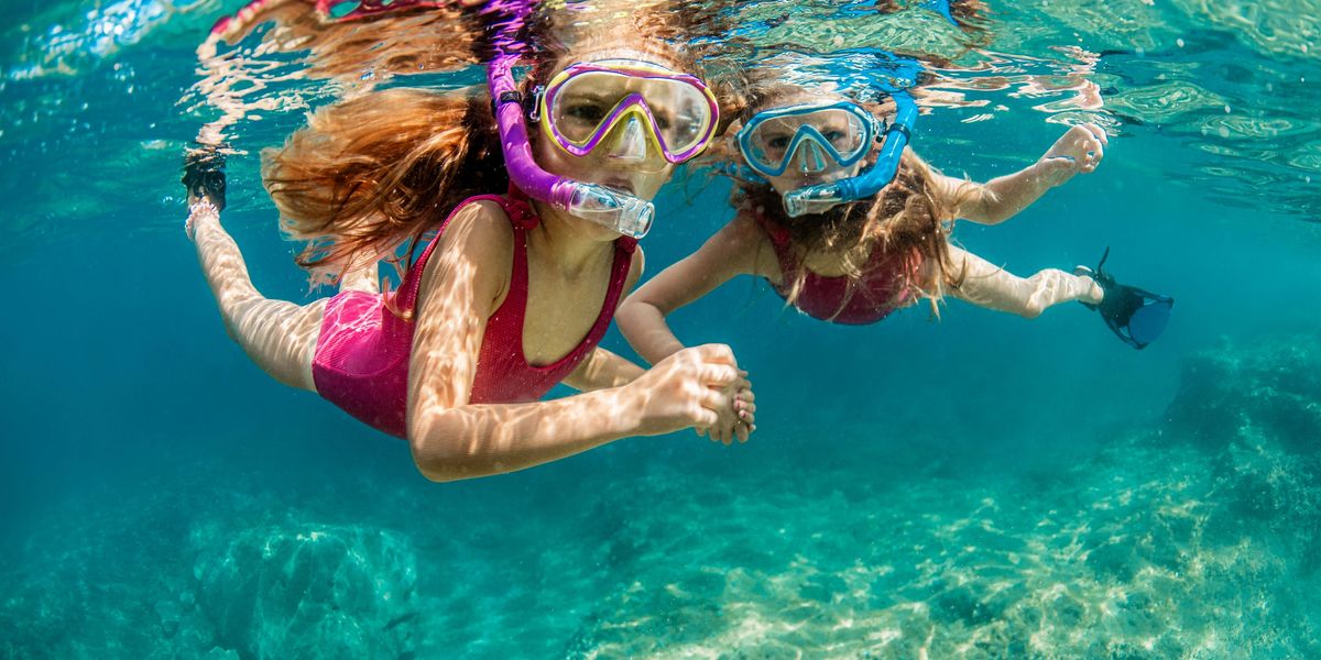 Two snorkelers swimming underwater through clear blue South Florida waters