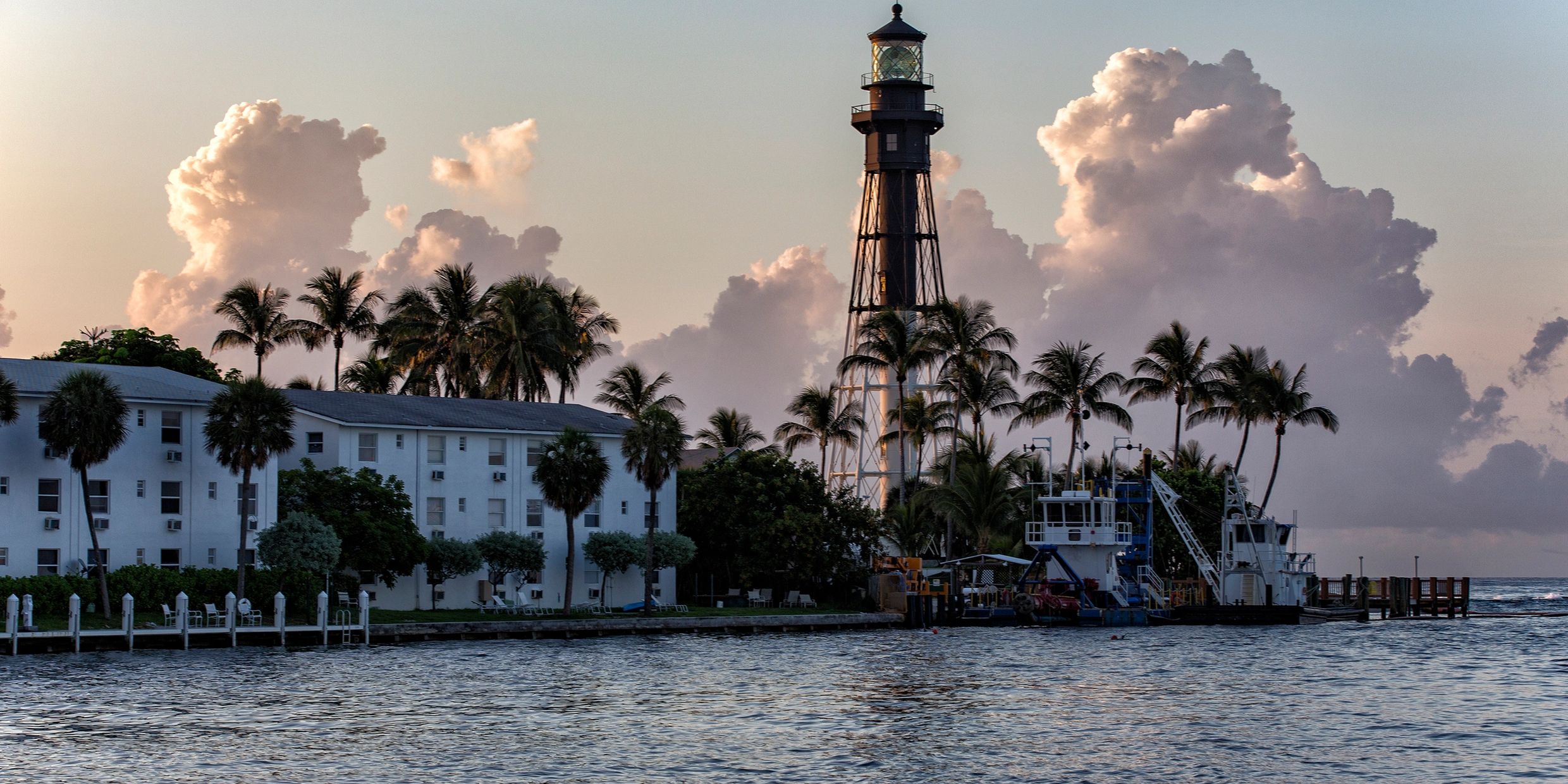 Hillsboro Lighthouse at dusk framed by palm trees on the South Florida Intracoastal